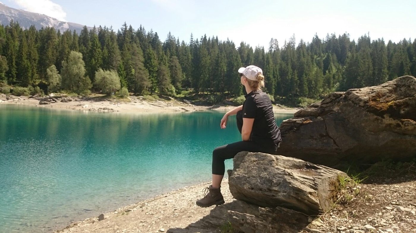 Christina Kehl on a rock by a turquoise mountain lake