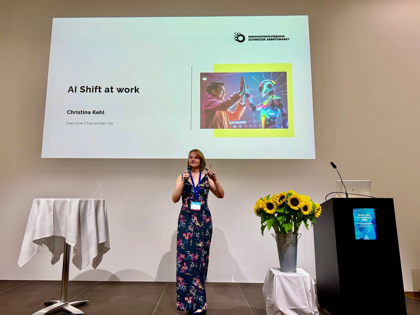 Christina Kehl on stage with a microphone in front of the slide “AI Shift at work”