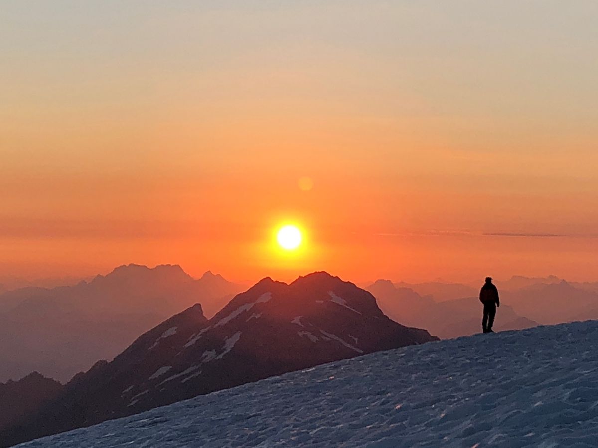 Sunrise over the mountains, a person standing on a snowy ridge